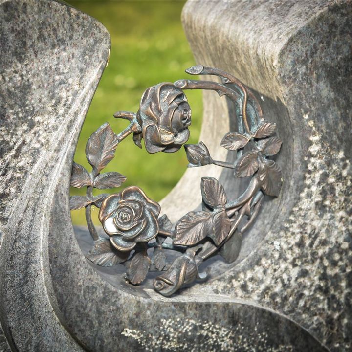 Eine Rose aus Metall die kunstvoll in den Grabstein integriert ist