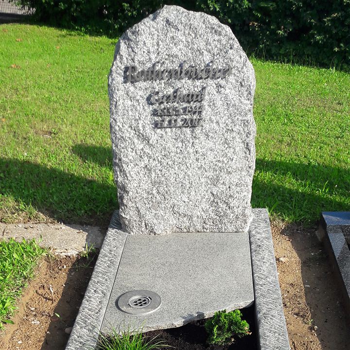 Ein weitestgehend naturbelassener Grabstein in hellgrau